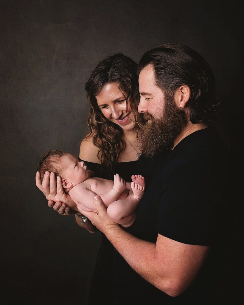 New parents smiling at their newborn during a fine art Nashville newborn photography session, capturing the love and connection of a growing family.