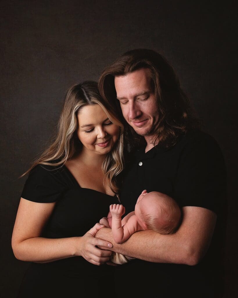 New parents admiring their newborn during a fine art Nashville newborn photography session, capturing the love and connection of a growing family.