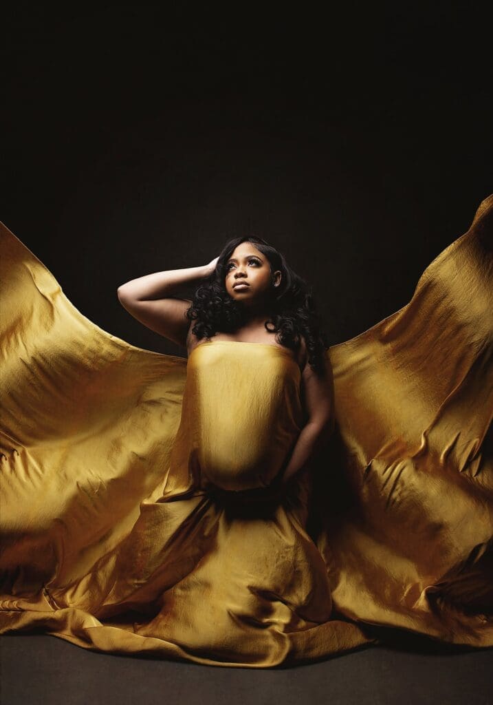 Dramatic studio maternity portrait featuring an expectant mother in flowing gold fabric during a luxury Nashville maternity photography session.