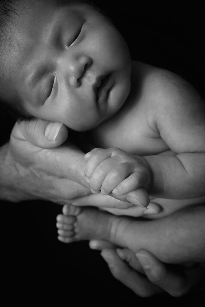 Black and white close-up portrait of a peacefully sleeping newborn baby resting safely in a parent's hands during a Nashville newborn photography session.