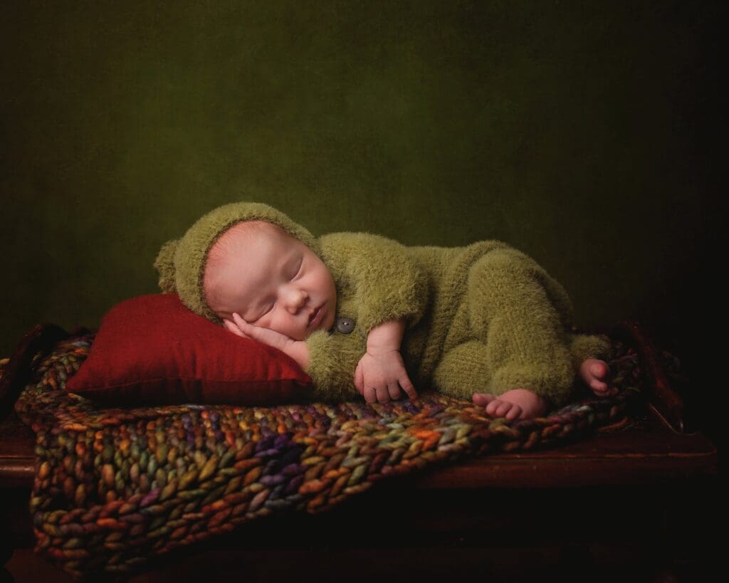 Newborn baby girl sleeping on a colorful vintage quilt during a fine art Nashville newborn photography session with heirloom-inspired styling.