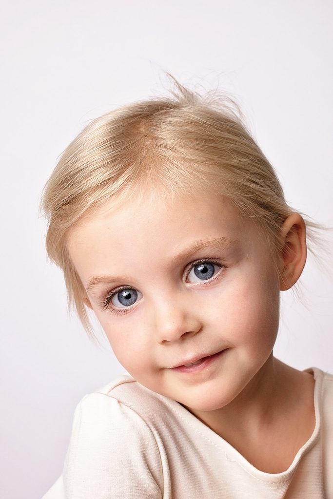 Close-up studio portrait of a young blonde girl with blue eyes by a Nashville child photographer.