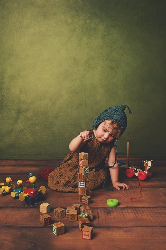 Toddler stacking vintage alphabet blocks and playing with colorful wooden toys during a Nashville child portrait session.
