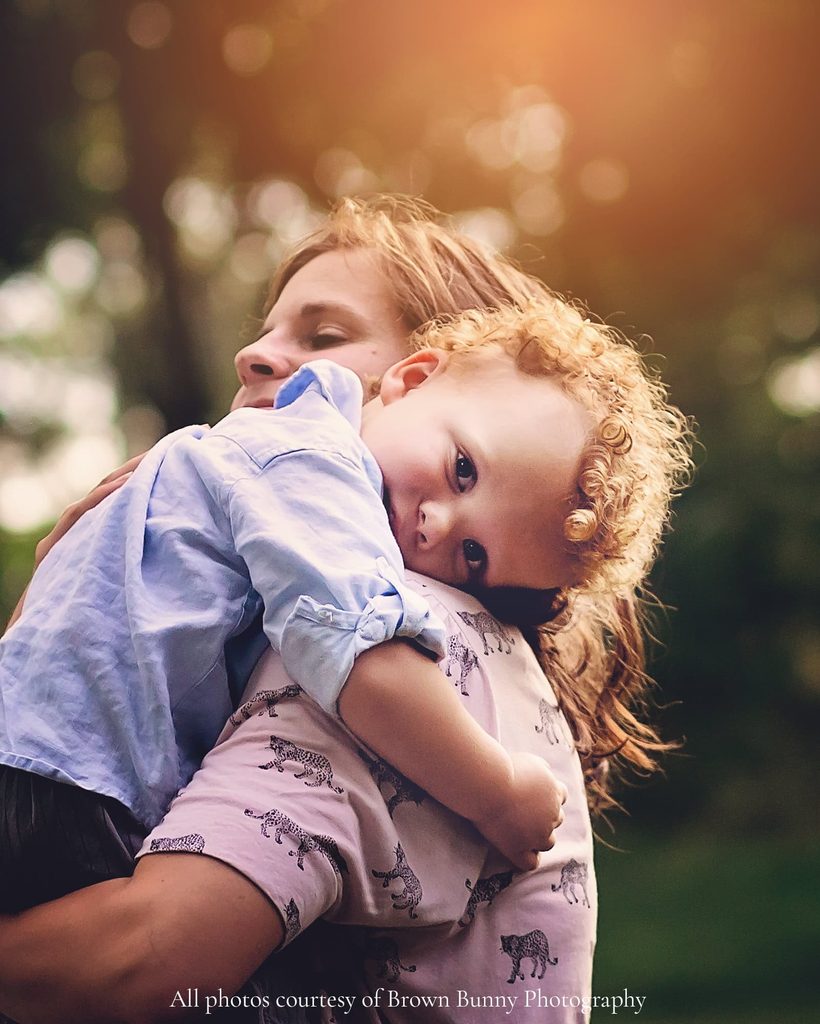 Curly-haired toddler resting his head on his mother’s shoulder during an emotional outdoor family portrait in Nashville.