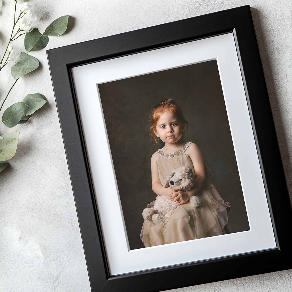 Fine art portrait of a young girl holding a teddy bear, displayed in a black archival frame with white matting by Brown Bunny Photography in Nashville.